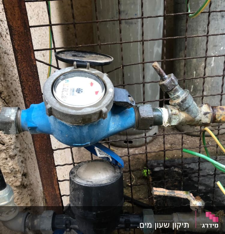 מונה מים כחול עם צינורות וברזים חלודים